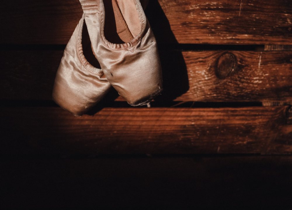Pointe shoes resting on a worn wooden floor
