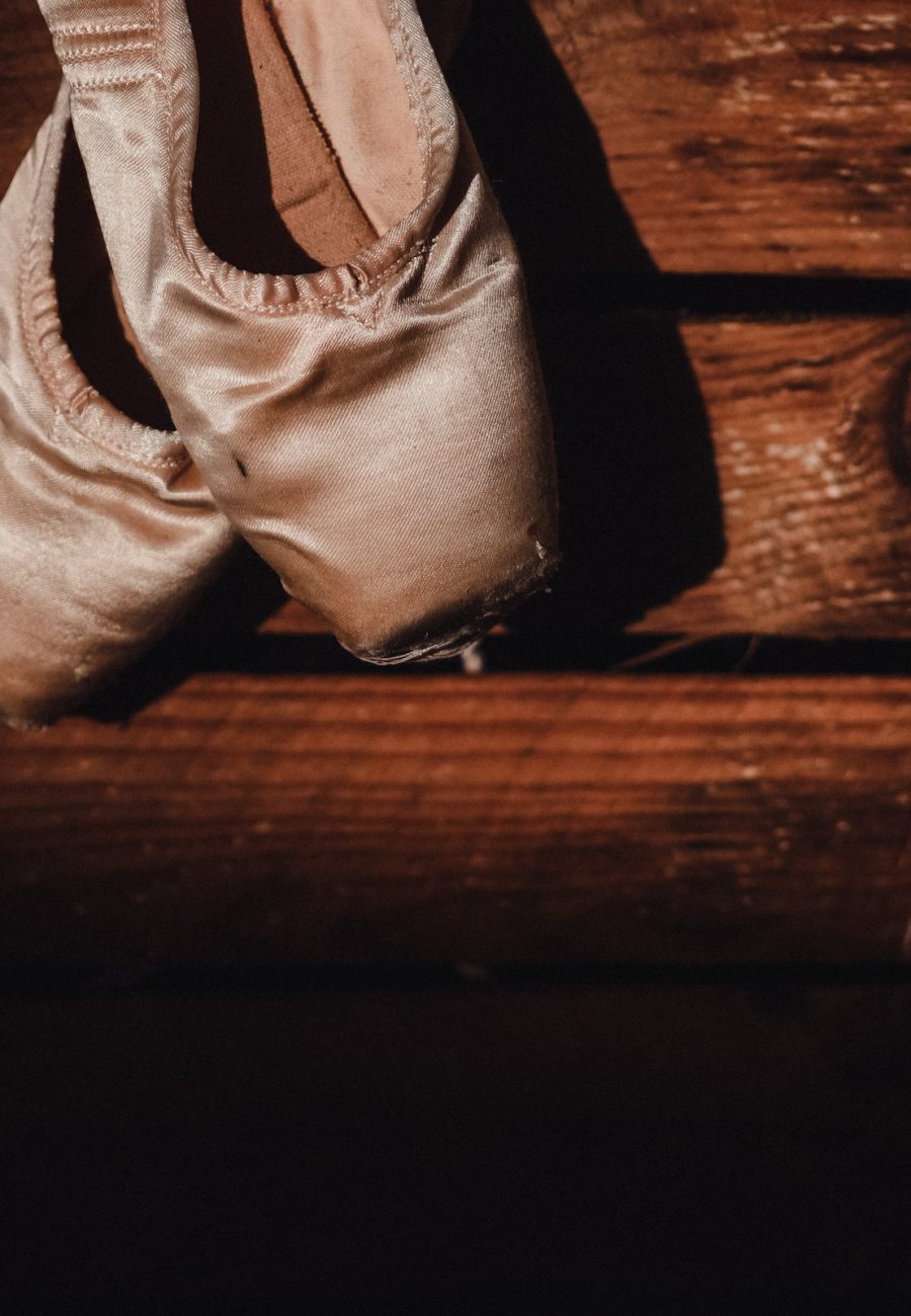 Pointe shoes resting on a worn wooden floor